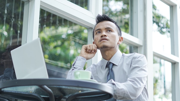 Los jóvenes empresarios piensan mientras se sientan con el portátil