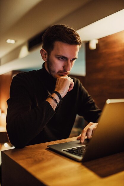 Jóvenes empresarios que usan laptop para reuniones en línea mientras están sentados en un café moderno.