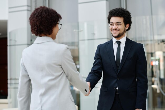 Jóvenes empresarios en ropa formal dándose la mano y saludándose antes de reunirse