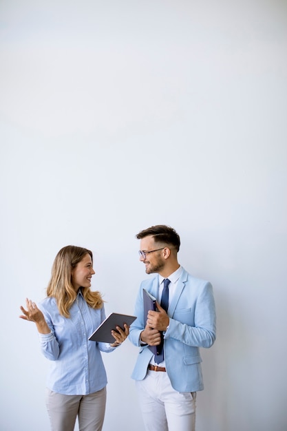 Jóvenes empresarios con tableta digital junto a la pared de la oficina