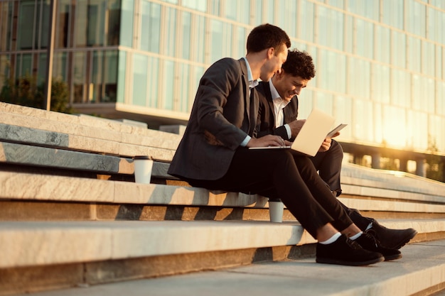 Jóvenes empresarios trabajan en una computadora portátil y responden los correos electrónicos de los clientes Dos empresarios cerca de la oficina