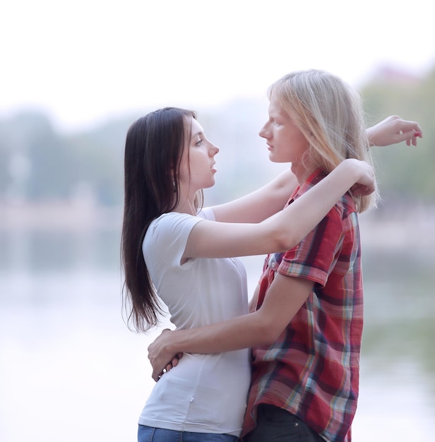 Jóvenes enamorados de pie en la orilla del lago