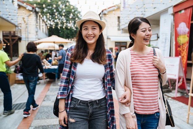 los jóvenes en espacios públicos abiertos descansan comunicación salud mental para residentes de la gran ciudad. dos chicas asiáticas mejores amigas los fines de semana de compras caminando por la calle en el mercado creativo de vacaciones día soleado