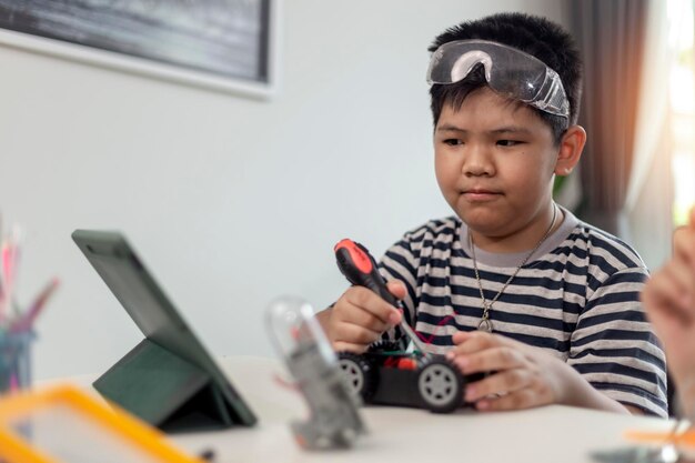 Jóvenes estudiantes asiáticos aprenden a distancia en línea en casa en codificación de automóviles robóticos y cables de placa electrónica en STEM STEAM matemáticas ingeniero de ciencia tecnología código de computadora en robótica para niños