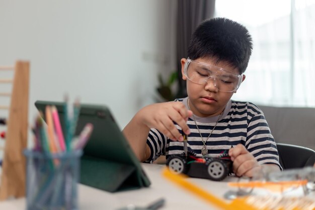 Jóvenes estudiantes asiáticos aprenden a distancia en línea en casa en codificación de automóviles robóticos y cables de placa electrónica en STEM STEAM matemáticas ingeniero de ciencia tecnología código de computadora en robótica para niños
