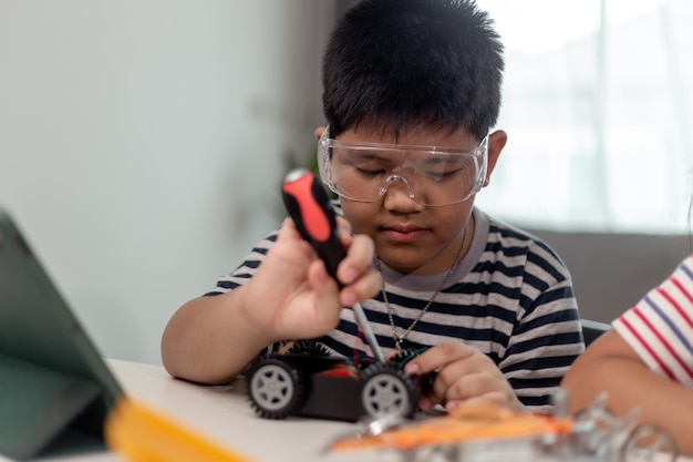 Jóvenes estudiantes asiáticos aprenden a distancia en línea en casa en codificación de automóviles robóticos y cables de placa electrónica en STEM STEAM matemáticas ingeniero de ciencia tecnología código de computadora en robótica para niños