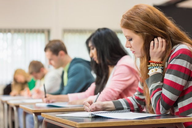 Jóvenes estudiantes escribiendo notas en el aula