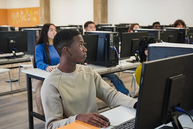 Jóvenes estudiantes multiétnicos que usan computadoras dentro del aula universitaria