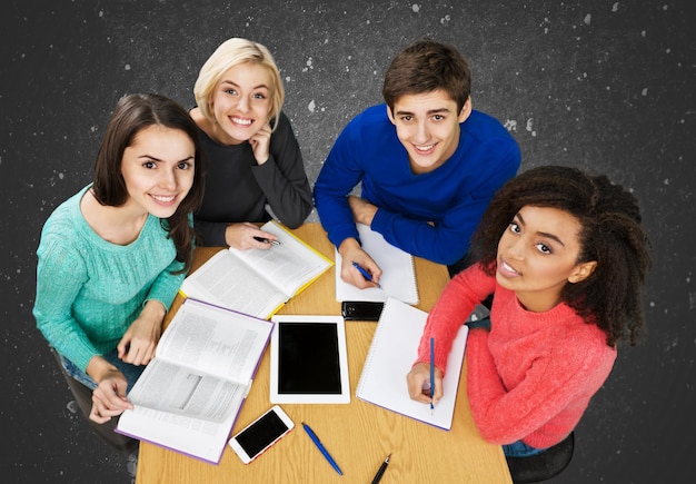 Jóvenes estudiantes que estudian sobre fondo oscuro