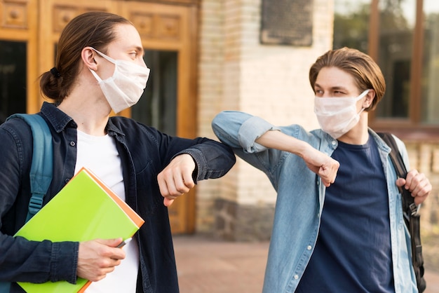 Foto jóvenes estudiantes tocando los codos en la universidad