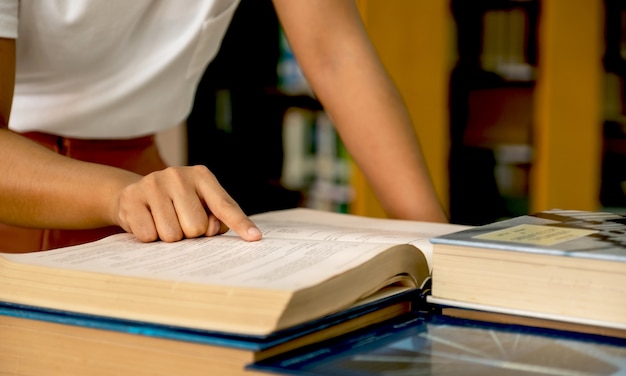 jóvenes estudiantes universitarias asiáticas señalando con la mano el libro para investigar y aprender de los libros de texto