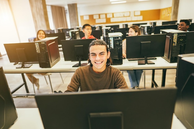 Jóvenes estudiantes usando computadoras dentro de la clase de tecnología en el aula Centrándose en la cara del chico central