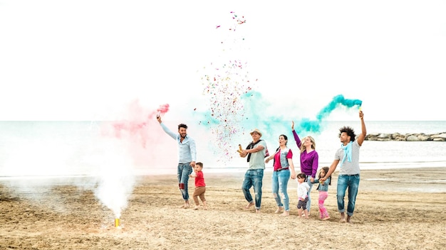 Jóvenes familias felices divirtiéndose en la playa con humor de fiesta con confeti y bengalas