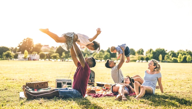 Jóvenes familias multirraciales que se divierten jugando con los niños en la fiesta de barbacoa pic nic