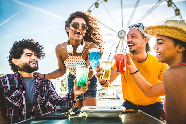 Jóvenes felices animando copas de cóctel juntos en la fiesta en la playa