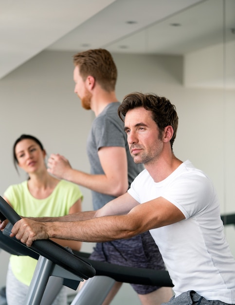 Jóvenes en forma feliz entrenamiento de cardio de la gente en el gimnasio