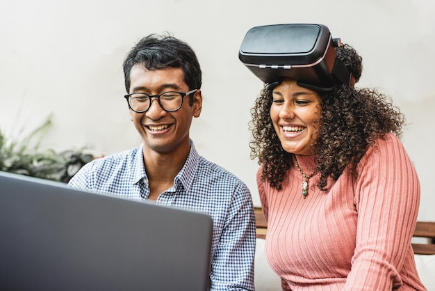 Jóvenes de la generación z que usan realidad aumentada dos personas birraciales que miran la pantalla de una computadora portátil para tener experiencia en realidad virtual y metaverso