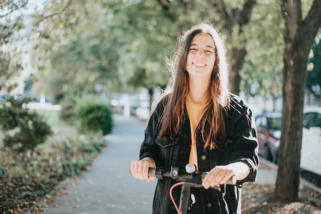 Jóvenes de la generación z que usan scooter eléctrico en el parque de la ciudad con espacio para copiar durante una puesta de sol