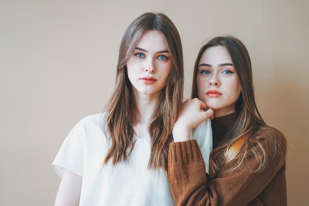 Jóvenes hermosas chicas de cabello largo hermanas gemelas en casual aislado sobre fondo beige