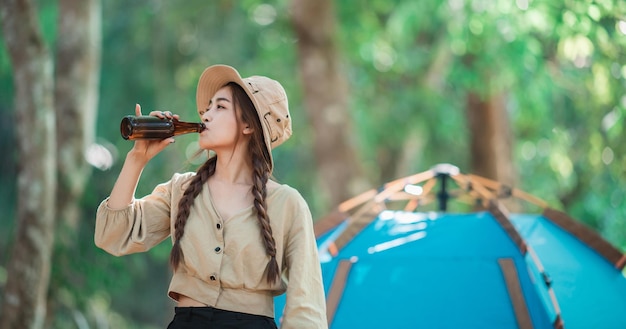 Jóvenes y hermosas mujeres asiáticas y amigas que viajan relajándose frente a una tienda de campaña Disfrutan hablando y bebiendo cerveza con diversión y felicidad juntas