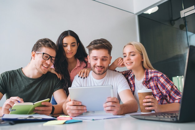 Jóvenes hermosos y atractivos se sientan juntos a la mesa