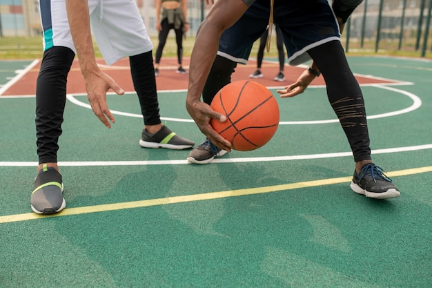 Uno de los jóvenes jugadores de baloncesto intercultural quitando el balón mientras lo sostiene sobre la cancha deportiva