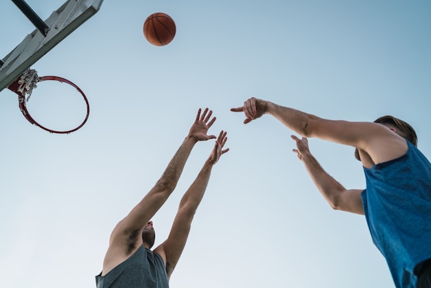 Jóvenes jugadores de baloncesto jugando uno a uno en la cancha al aire libre. Concepto de deporte y baloncesto.