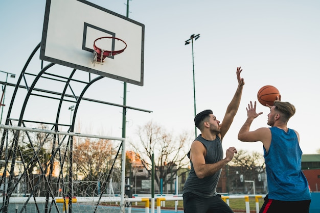 Jóvenes jugadores de baloncesto jugando uno a uno.