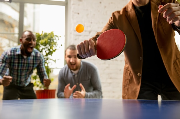 Foto jóvenes jugando al tenis de mesa en el lugar de trabajo, divirtiéndose