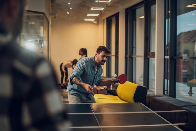 Jóvenes jugando tenis de mesa en la oficina en el trabajo