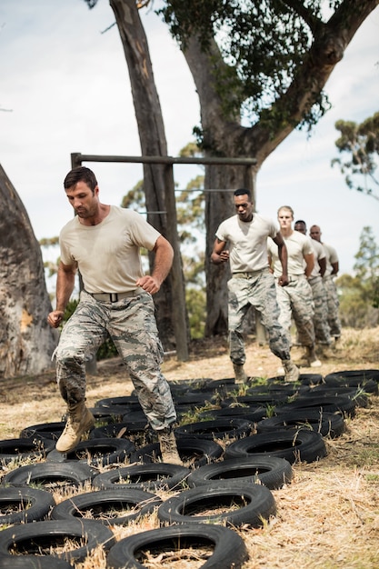 Foto jóvenes militares practicando carrera de obstáculos de neumáticos