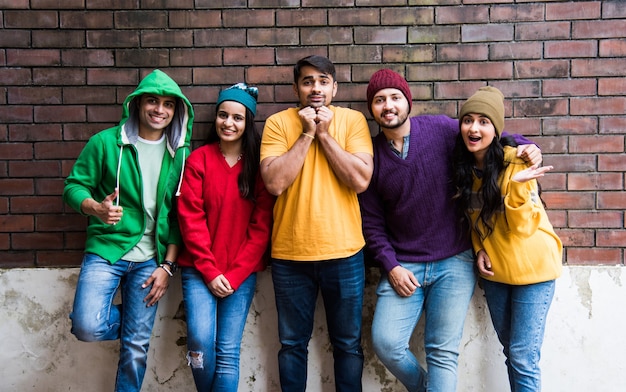 Jóvenes modelos asiáticos indios o amigos posando mientras usan coloridos suéteres y sombreros de lana