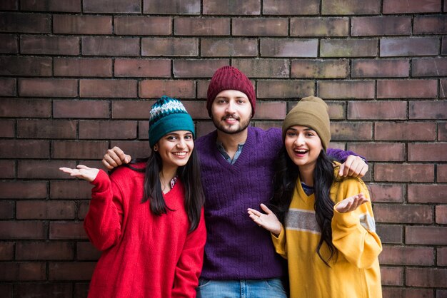 Jóvenes modelos asiáticos indios o amigos posando mientras usan coloridos suéteres y sombreros de lana