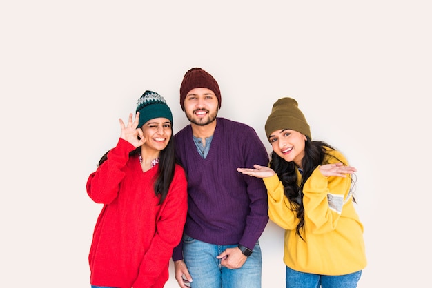 Jóvenes modelos asiáticos indios o amigos posando mientras usan coloridos suéteres y sombreros de lana