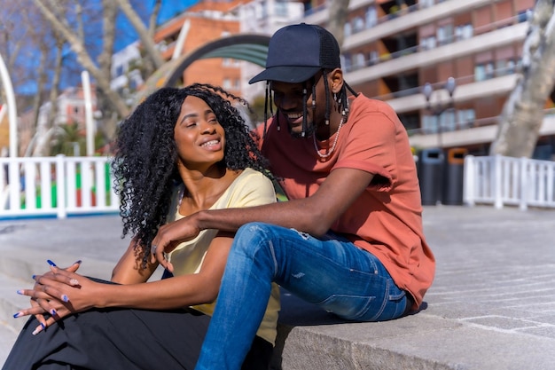 Jóvenes mujeres afroamericanas en el concepto de estilo de vida de la ciudad amigos sentados en un parque riendo