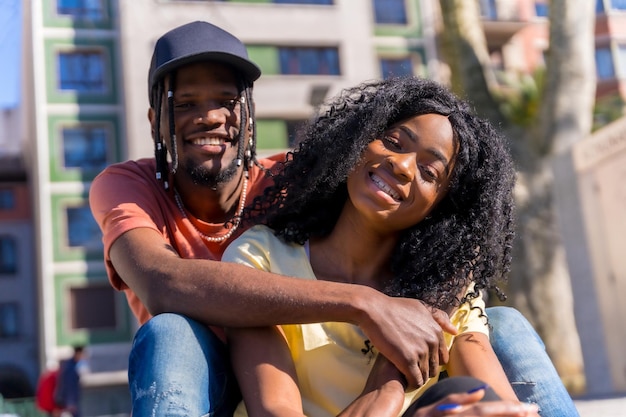 Jóvenes mujeres afroamericanas en el concepto de estilo de vida de la ciudad amigos sentados en un parque sonriendo