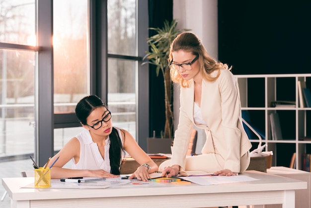 jóvenes mujeres de negocios multiétnicas con ropa formal hablando en una oficina moderna