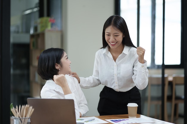 Jóvenes mujeres de negocios profesionales e inteligentes celebrando juntos después de recibir las buenas noticias del gran proyecto