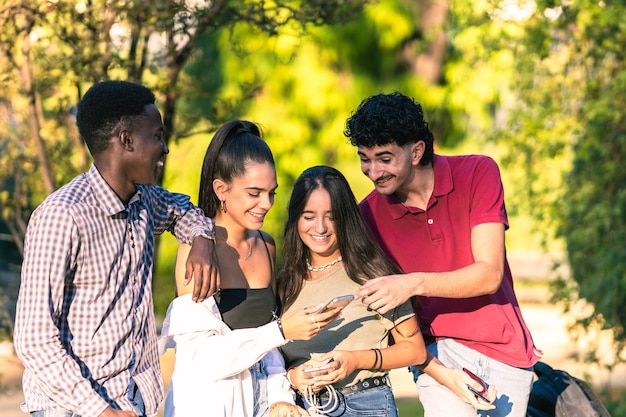 Jóvenes multiétnicos mirando un teléfono móvil mientras sonríen al aire libre