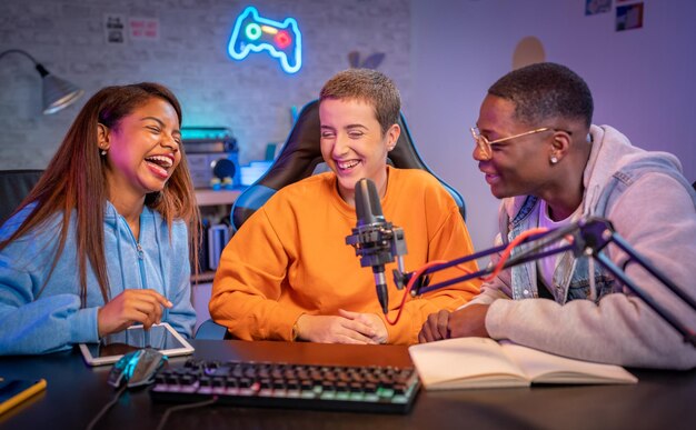 Jóvenes multirraciales felices actuando en un programa de radio grabando podcasts para un programa en línea