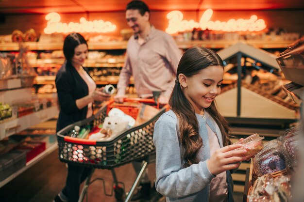 Jóvenes padres e hija en la tienda de comestibles