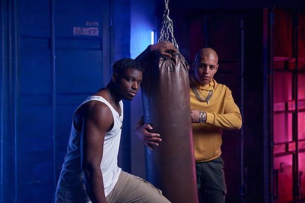 Foto jóvenes de la pandilla entrenando con saco de boxeo en el garaje.