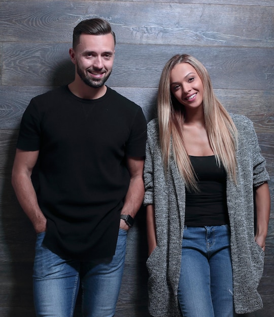 Los jóvenes se paran cerca de la camiseta ligera de jeans de pared