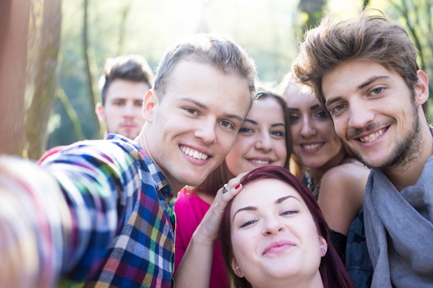 Jóvenes pasando un buen rato juntos en el parque en el río y tomando selfie