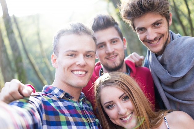 Jóvenes pasando un buen rato juntos en el parque en el río y tomando selfie