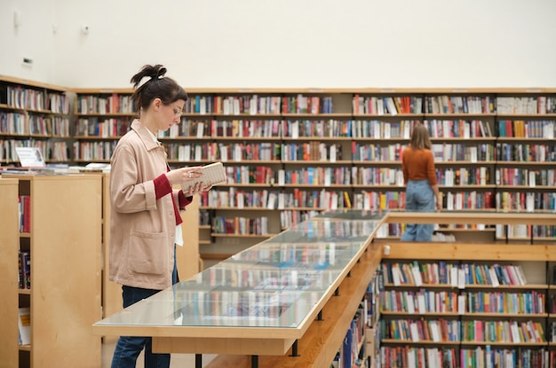 Jóvenes que estudian en la biblioteca y eligen libros para leer.