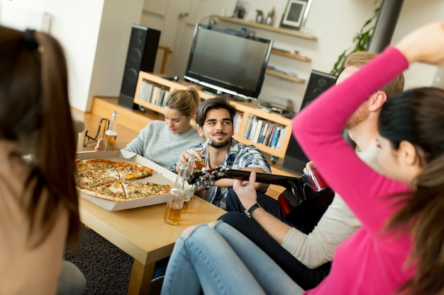 Los jóvenes que tienen fiesta de pizza en la habitación