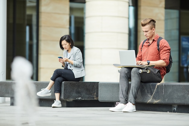 Jóvenes que usan dispositivos electrónicos en la ciudad