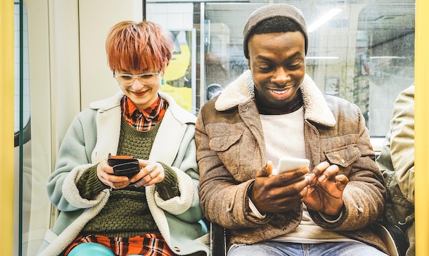 Jóvenes que usan teléfonos inteligentes mientras están sentados en el interior