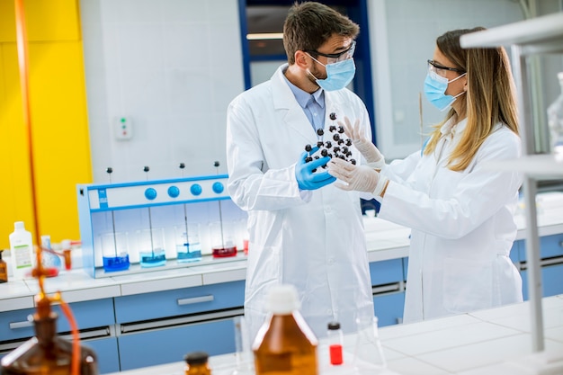 Foto jóvenes químicos con gafas de seguridad tienen modelo molecular en el laboratorio